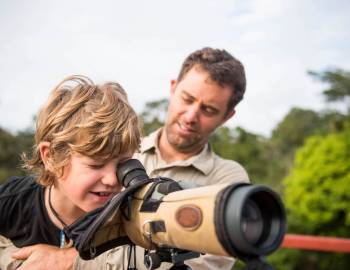 little boy looking through camera at nature preserve